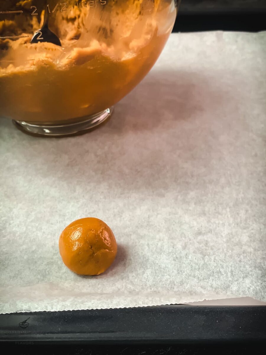 Peanut butter cookie dough ball on parchment paper.