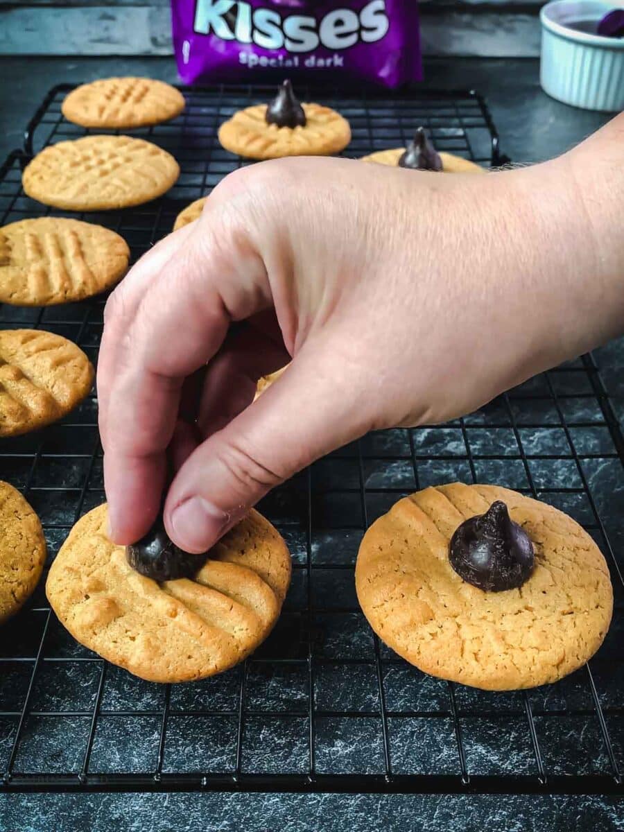 Place the Hershey dark chocolate kiss on the warm peanut butter cookie.