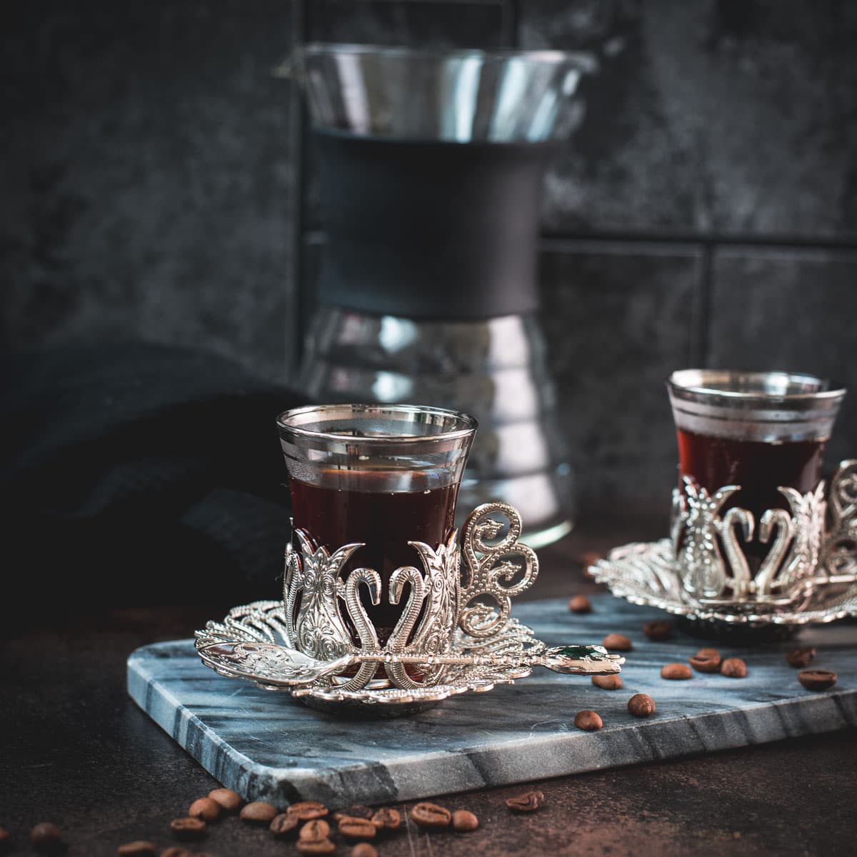 Gorgeous medieval glass filled with delicious specialty coffee placed on marbled plate.