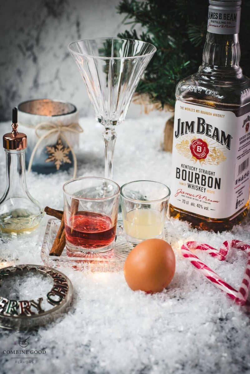 Cranberry cinnamon whiskey sour ingredients - egg white, lemon juice, whiskey, cranberry juice, orange bitters, and a dash of ground cinnamon.