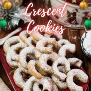 Delicious traditional Austrian vanilla crescents stacked on christmassy plate, placed next to a Christmass cookie jar.