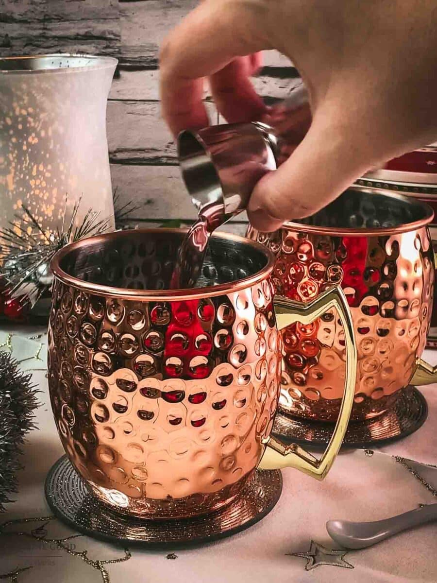 Add cranberry juice to the copper mugs.