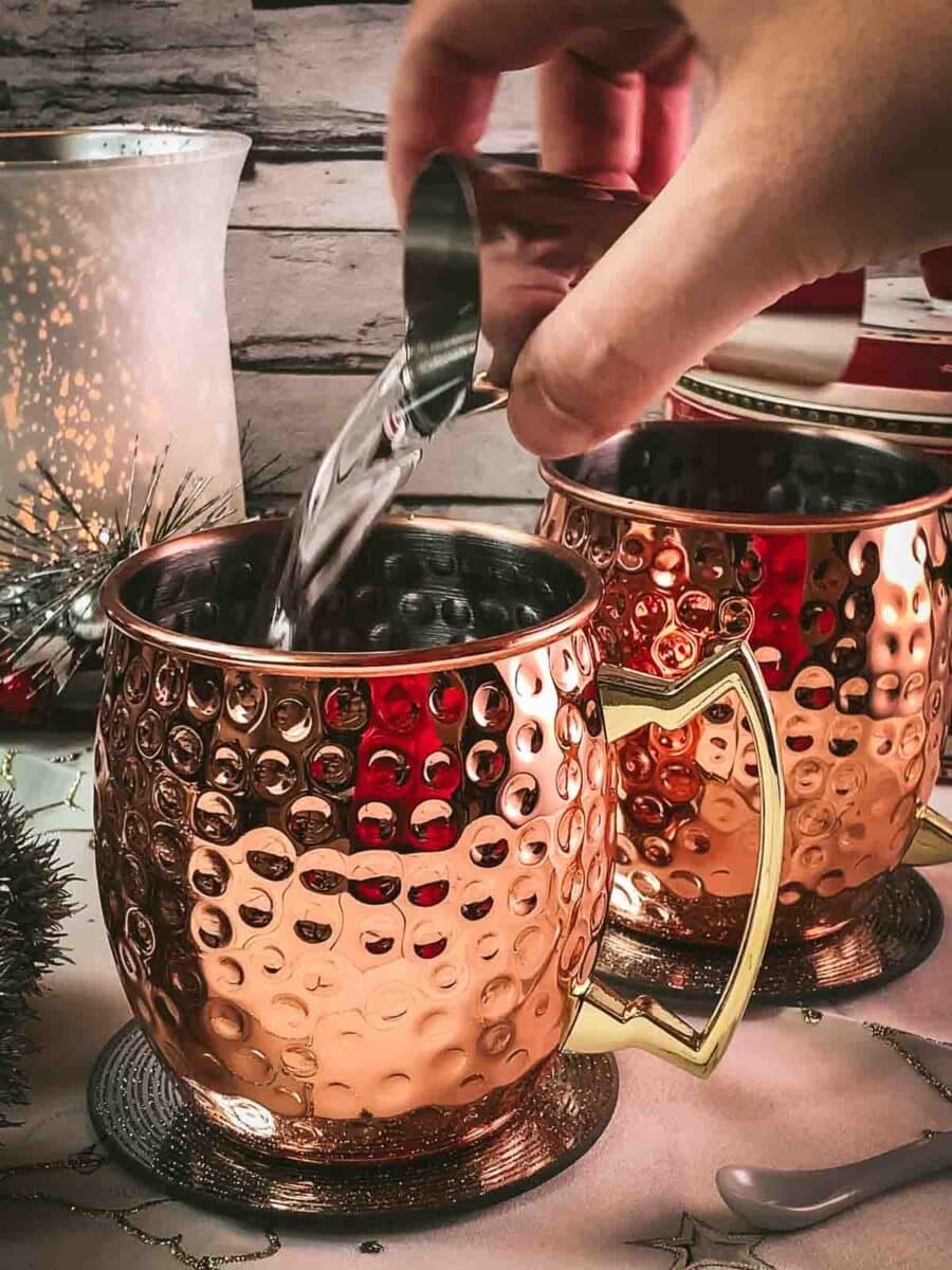 Add vodka to the copper mugs.