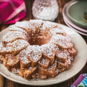 Gorgeous six egg yolk bundt cake, dusted with powdered sugar, and placed on white plate.