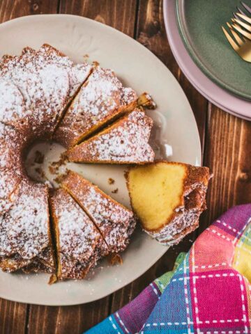 Gorgeous six egg yolk bundt cake, dusted with powdered sugar, and placed on white plate.