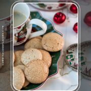 Delicious hazelnut meringue cookies placed on green christmassy plate, next to a coffee mug.