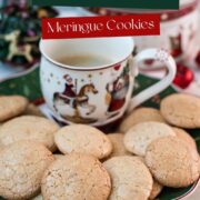 Delicious hazelnut meringue cookies placed on green christmassy plate, next to a coffee mug.