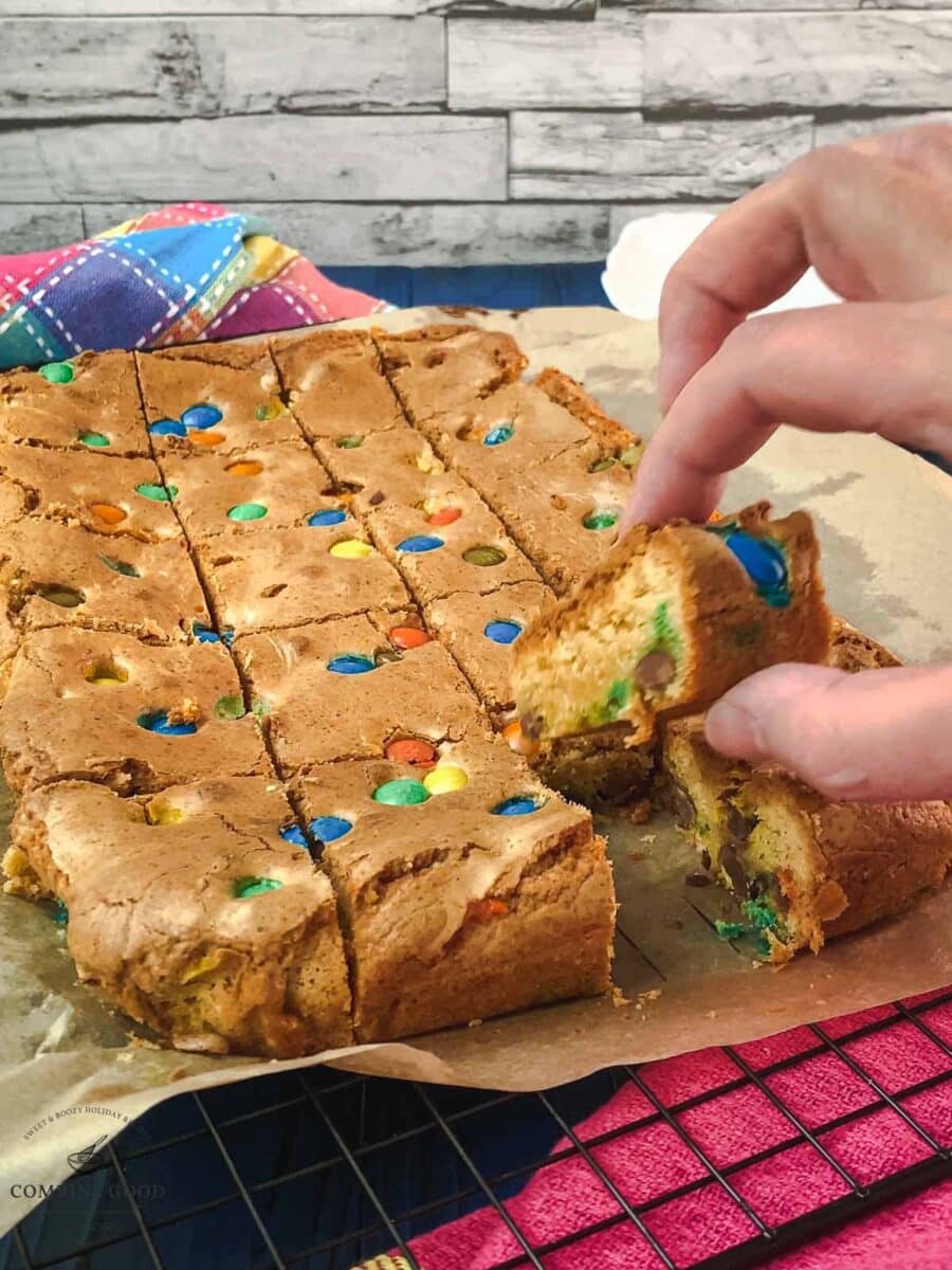 Hand taking a M&M cookie bar after slicing.