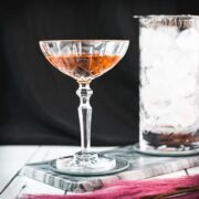 Sophisticated Manhattan cocktail, garnished with a Maraschino cherry, placed on a marbled plate.