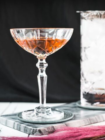 Sophisticated Manhattan cocktail, garnished with a Maraschino cherry, placed on a marbled plate.