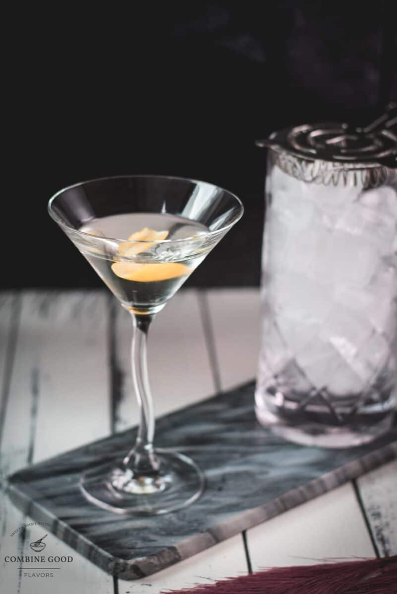 Elegant cocktail glass, placed on marbled plate, and garnished with a lemon zest.