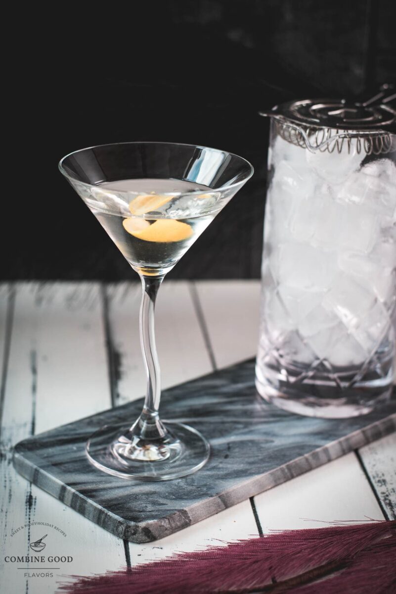 Elegant cocktail glass, placed on marbled plate, and garnished with a lemon zest.