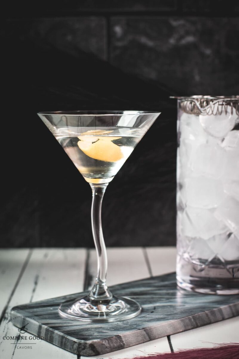 Elegant cocktail glass, placed on marbled plate, and garnished with a lemon zest.