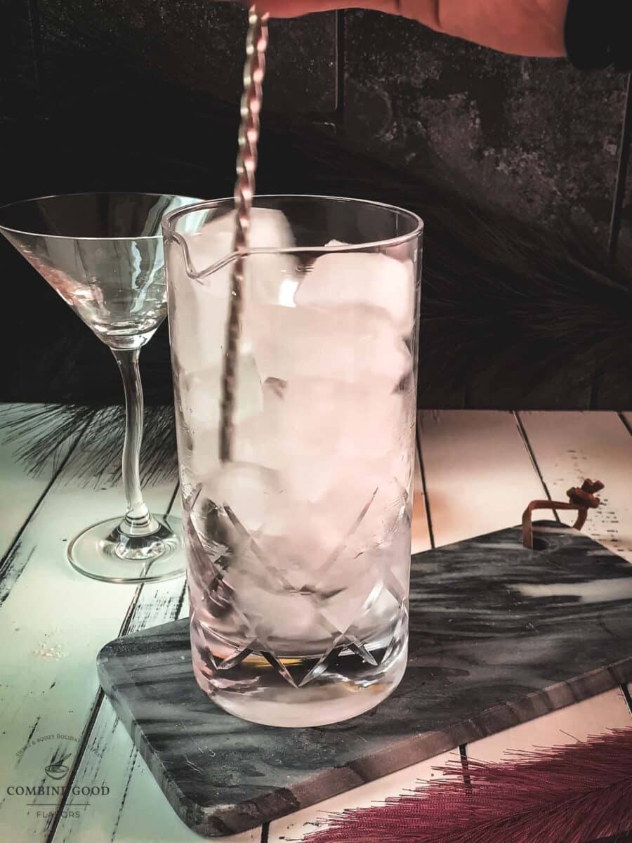 Elegant cocktail glass, placed on marbled plate, and garnished with a lemon zest.