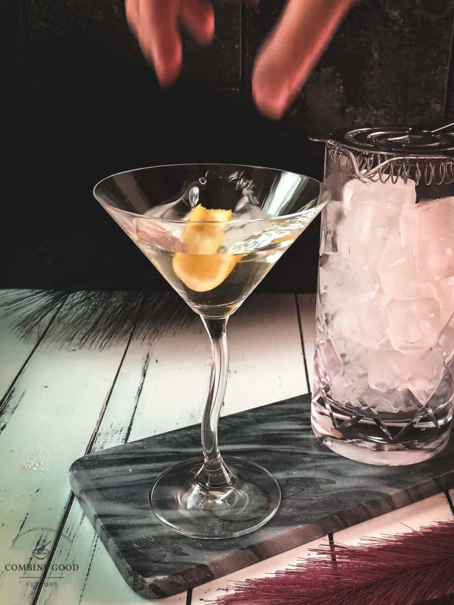 Elegant cocktail glass, placed on marbled plate, and garnished with a lemon zest.