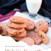 Gorgeous pink cookies on white plate, next to a glass on milk.