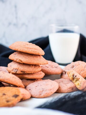 Gorgeous pink cookies on white plate, next to a glass on milk.