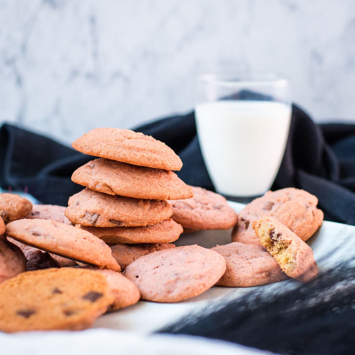 Gorgeous pink cookies on white plate, next to a glass on milk.