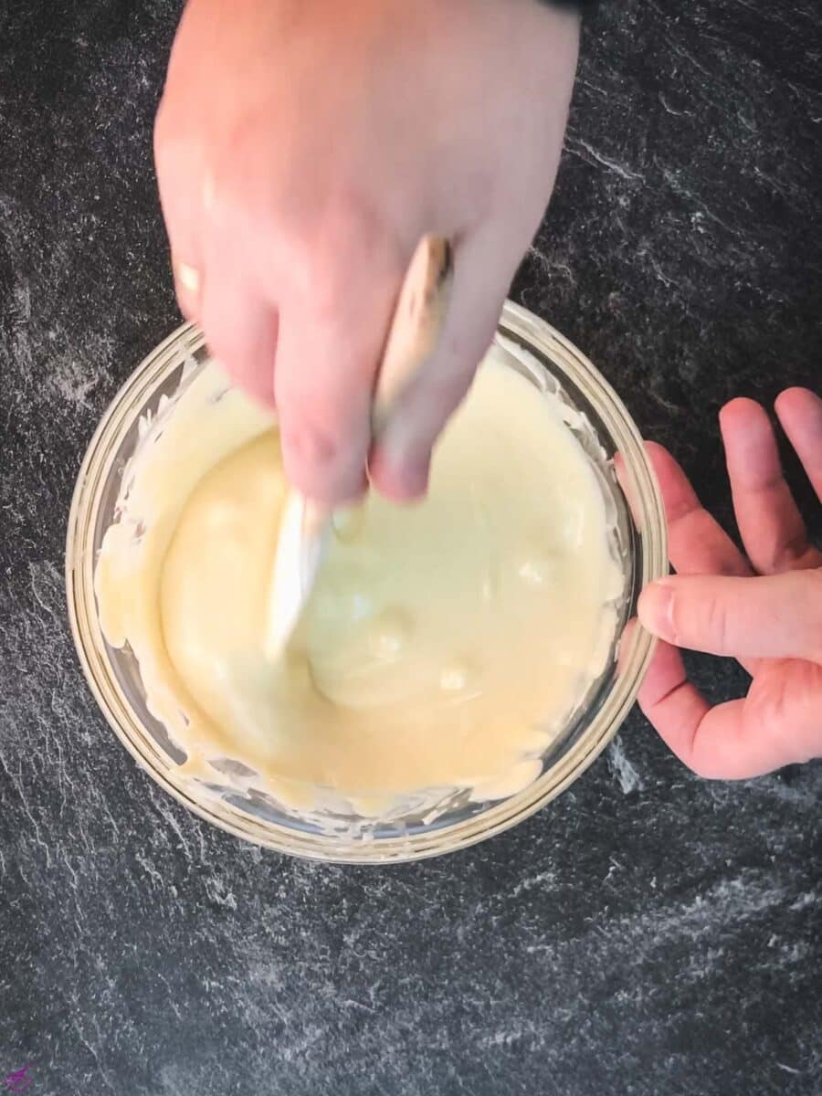 Melt the white chocolate ganache, stirring it with a spatula until smooth.