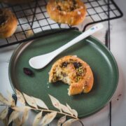 A delicious, half-eaten mini pistachio sweet roll on a green plate.