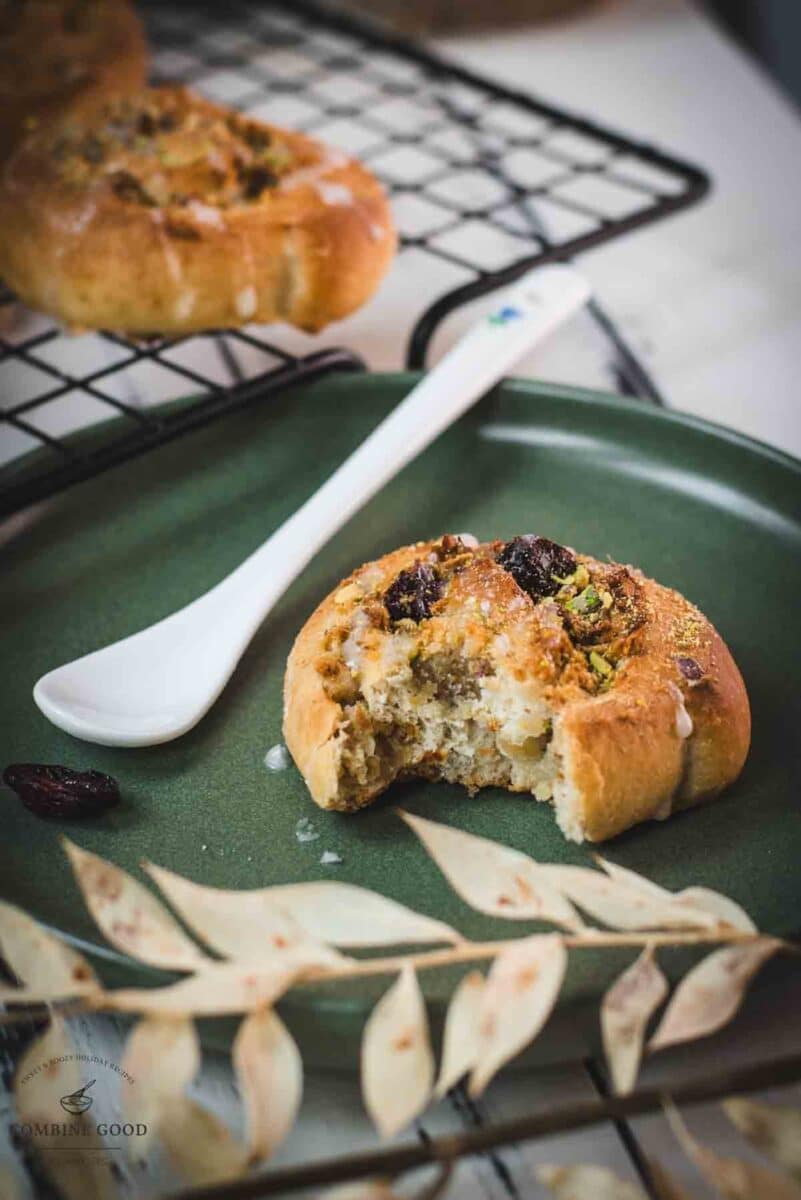 A delicious, half-eaten mini pistachio sweet roll on a green plate.