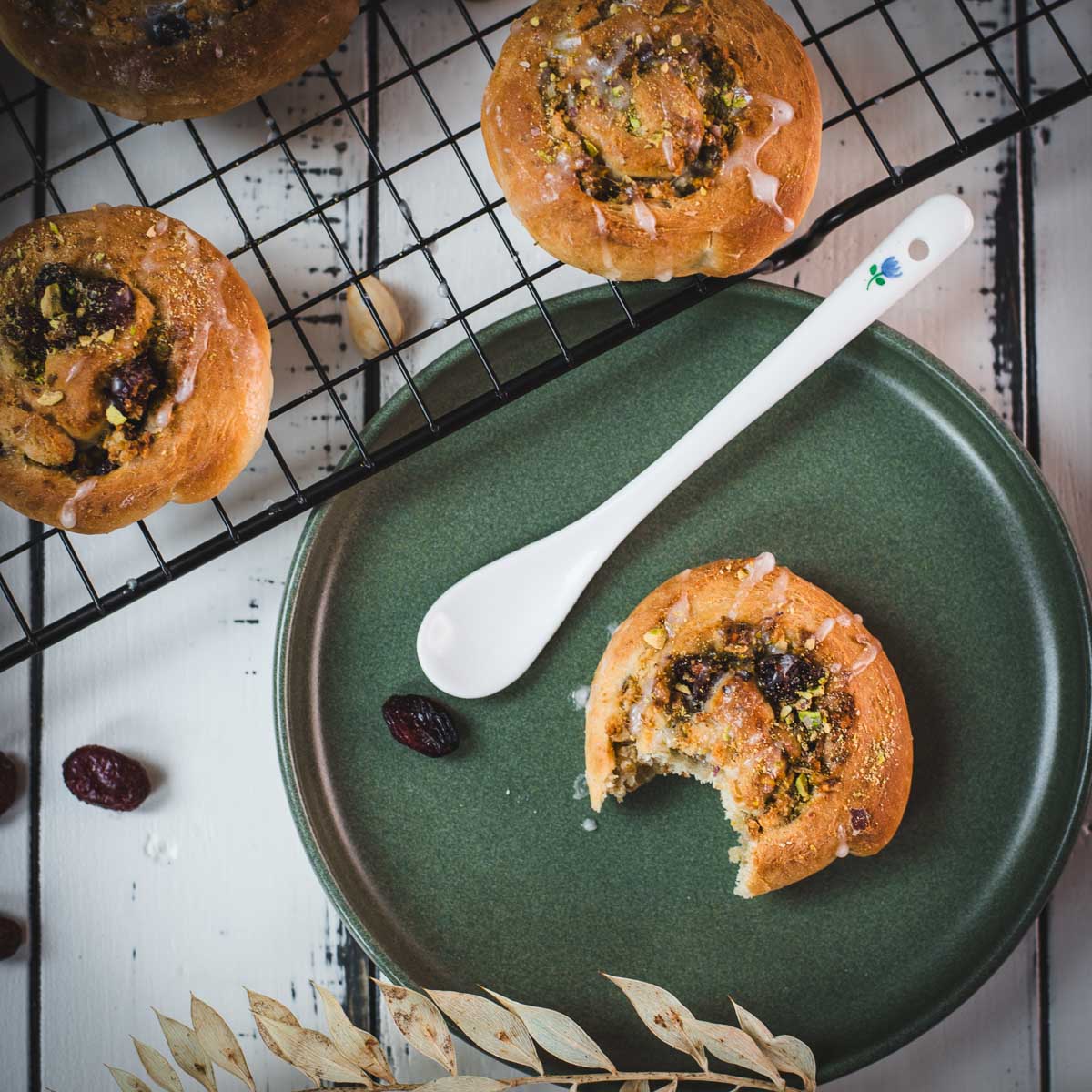 A delicious, half-eaten mini pistachio sweet roll on a green plate.