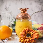 Classic screwdriver cocktail, served in pineapple shaped cocktail glass, placed next to an orange flower.