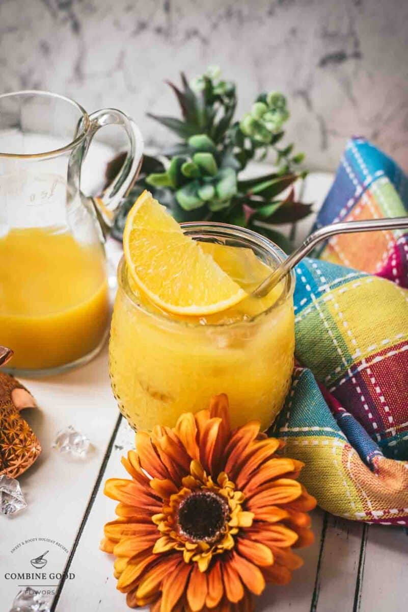 Classic screwdriver cocktail, served in pineapple shaped cocktail glass, placed next to an orange flower.