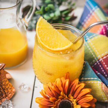 Classic screwdriver cocktail, served in pineapple shaped cocktail glass, placed next to an orange flower.