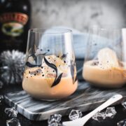 Cute tumbler glasses filled with delicious Baileys Irish Cream on the rocks. Placed on marbled plate.