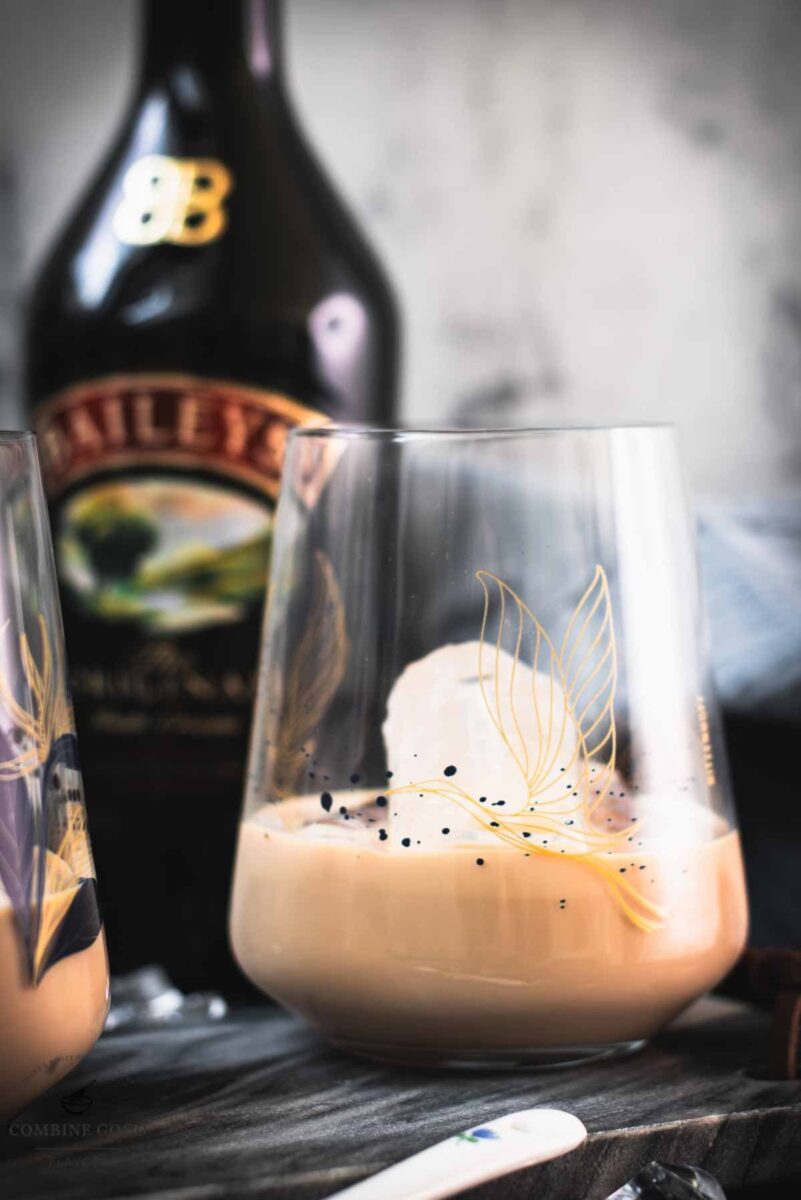 Cute tumbler glasses filled with delicious Baileys Irish Cream on the rocks. Placed on marbled plate.