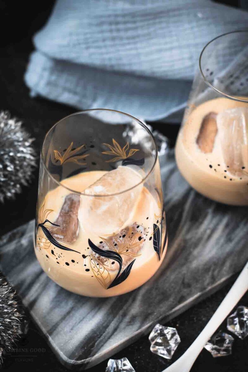 Cute tumbler glasses filled with delicious Baileys Irish Cream on the rocks. Placed on marbled plate.