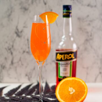 Gorgeous sparkling wine glass, with engraved heart and two crystals, filled with delicious Aperol Mimosa. Placed on heartshaped black slate coaster.