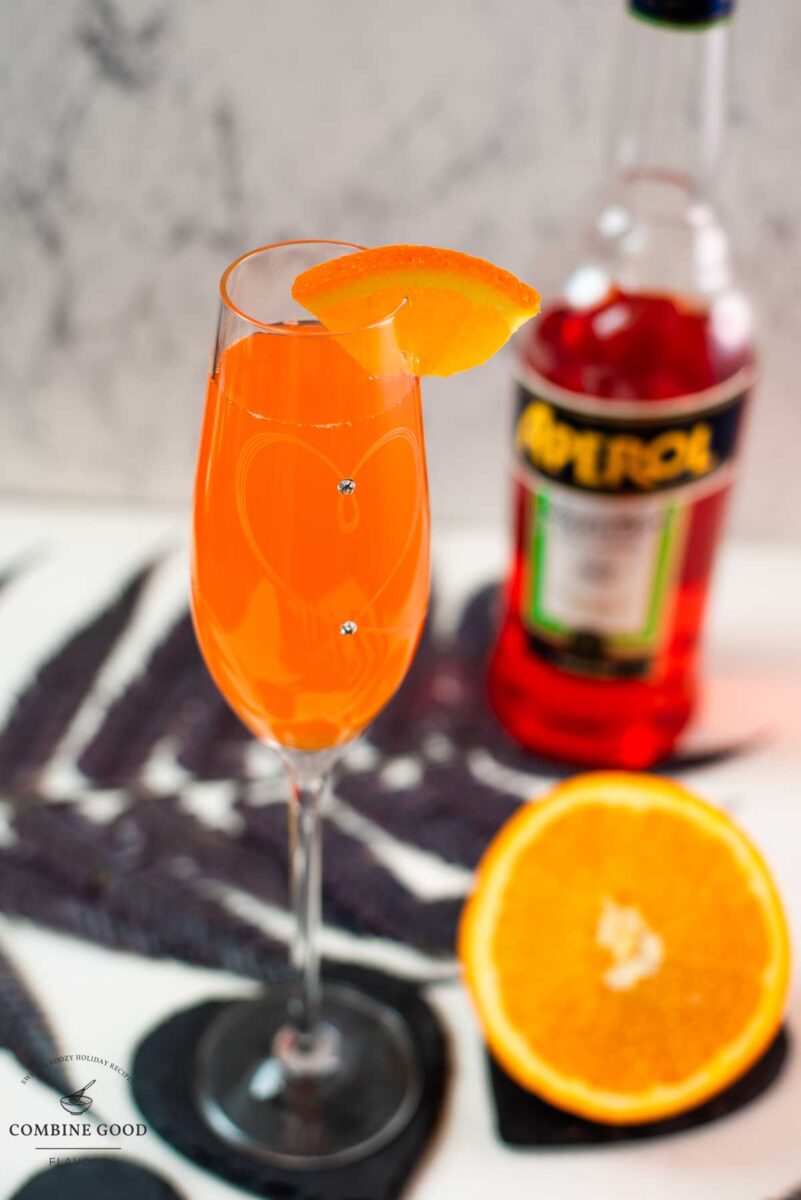 Gorgeous sparkling wine glass, with engraved heart and two crystals, filled with delicious Aperol Mimosa. Placed on heartshaped black slate coaster.