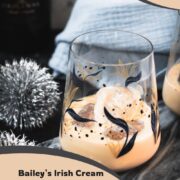 Cute tumbler glasses filled with delicious Baileys Irish Cream on the rocks. Placed on marbled plate.