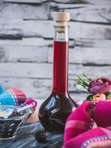 Delicious homemade Chambord, blackberry raspberry liqueur, on gorgeous flask, placed on black slate.