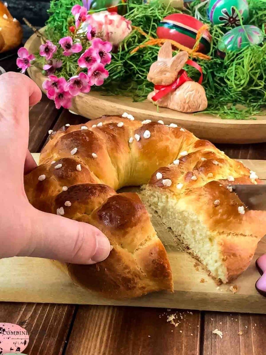 Gorgeous braided Easter bread wreath, placed on wooden cutting board, next to easter decoration.