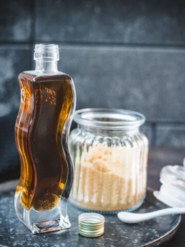Gorgeous, curved bottle, filled with delicious brown sugar simple syrup. Placed on dark plate.