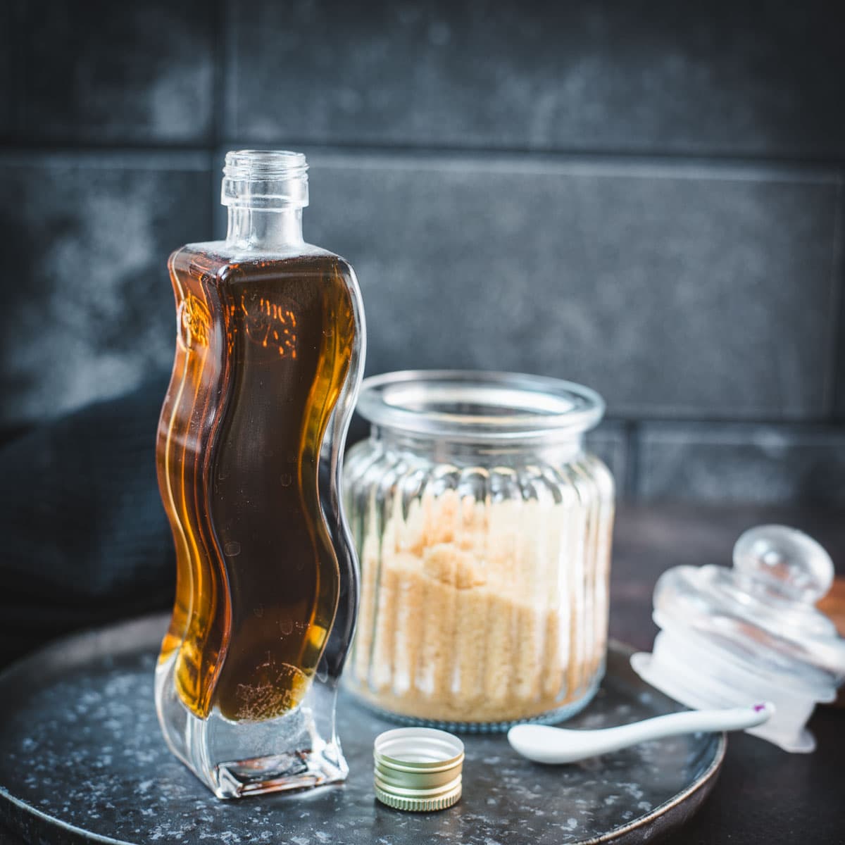 Gorgeous, curved bottle, filled with delicious brown sugar simple syrup. Placed on dark plate.