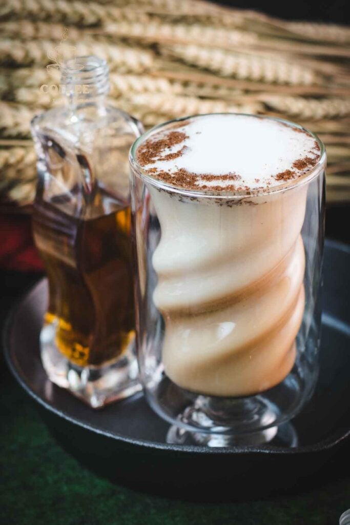 Curved glass filled with delicious brown sugar cinnamon latte, placed in a cast iron pan on a green felt base.
