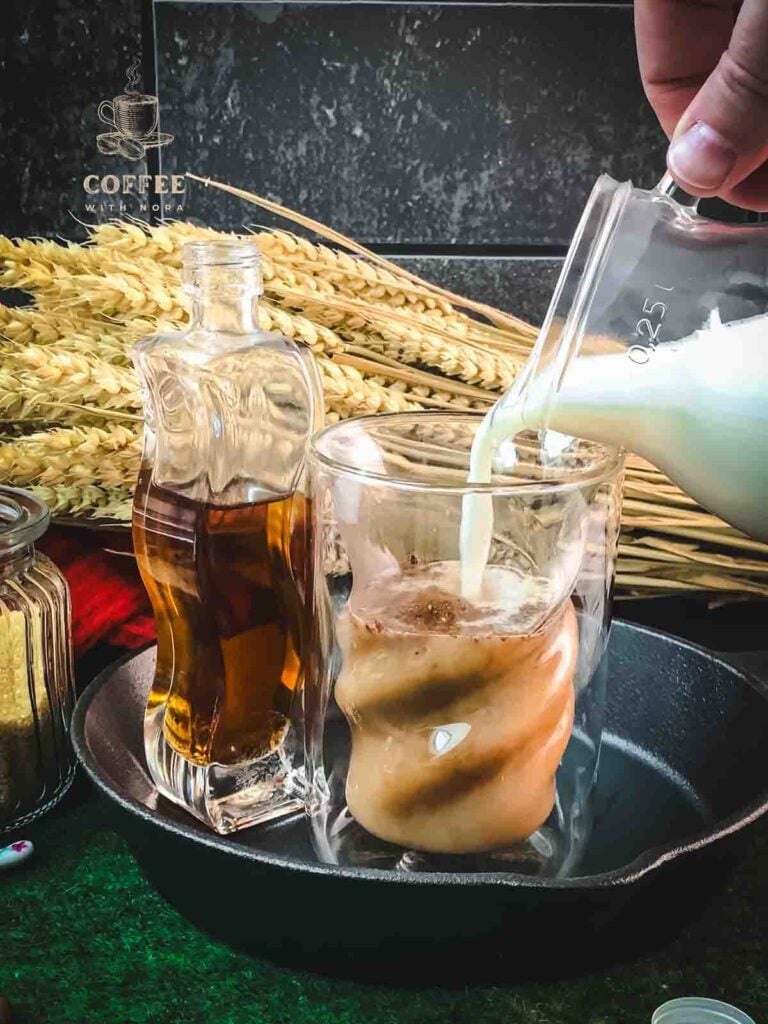 Pour the hot milk into the glass filled with Espresso, cinnamon, and brown sugar simple syrup.