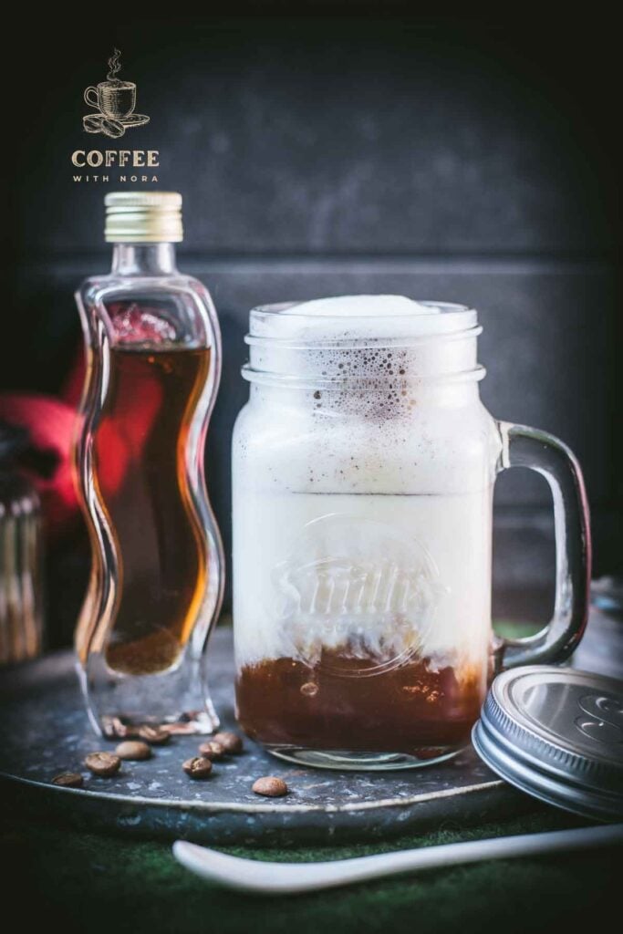 Homemade brown sugar shaken espresso, served in a mason jar. Placed next to a homemade brown sugar simple syrup bottle.
