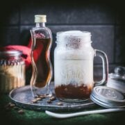 Homemade brown sugar shaken espresso, served in a mason jar. Placed next to a homemade brown sugar simple syrup bottle.