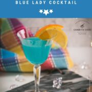 Gorgeous blue lady cocktail, served in vintage glass, garnished with an orange and an lemon slice side by side. Placed on a marbled plate.