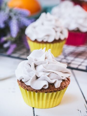 Ready to serve orange muffins with lavender buttercream. Placed on white wooden ground.