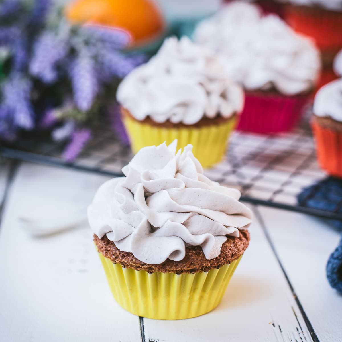Ready to serve orange muffins with lavender buttercream. Placed on white wooden ground.