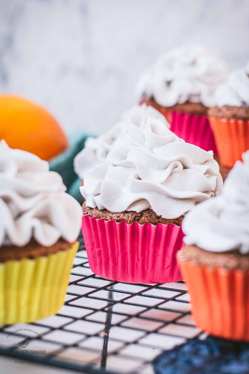 Ready to serve orange muffins with lavender buttercream. Placed on cooling rack.