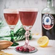 Divine ruby fizz cocktail, placed on mirrored coaster and served in a red and a green glass.