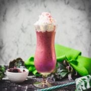 Boozy berry adult milkshake with homemade Chambord, served in Hurricane glass. Garnished with whipped cream and dusted with edible glitter. Served with a drinking straw.