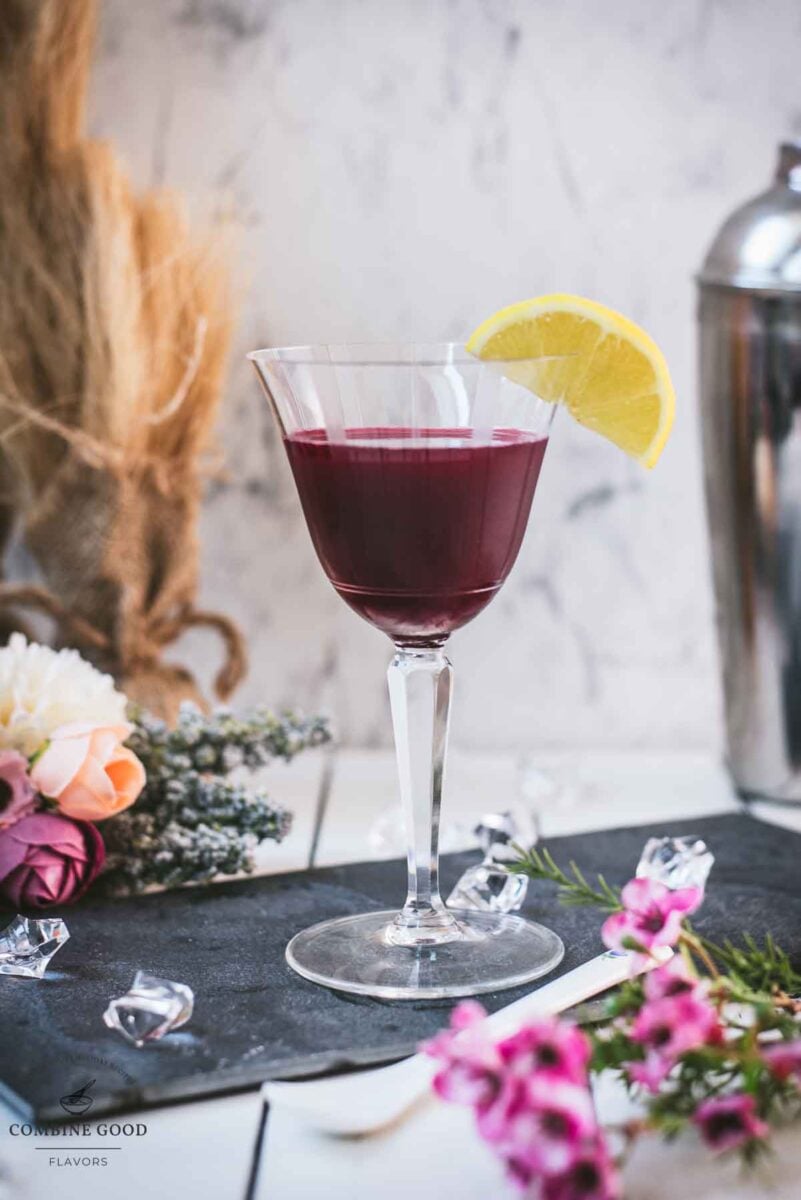 Elegant, dark red beetroot sour, garnished with a lemon wedge. Placed on a black slate plate.